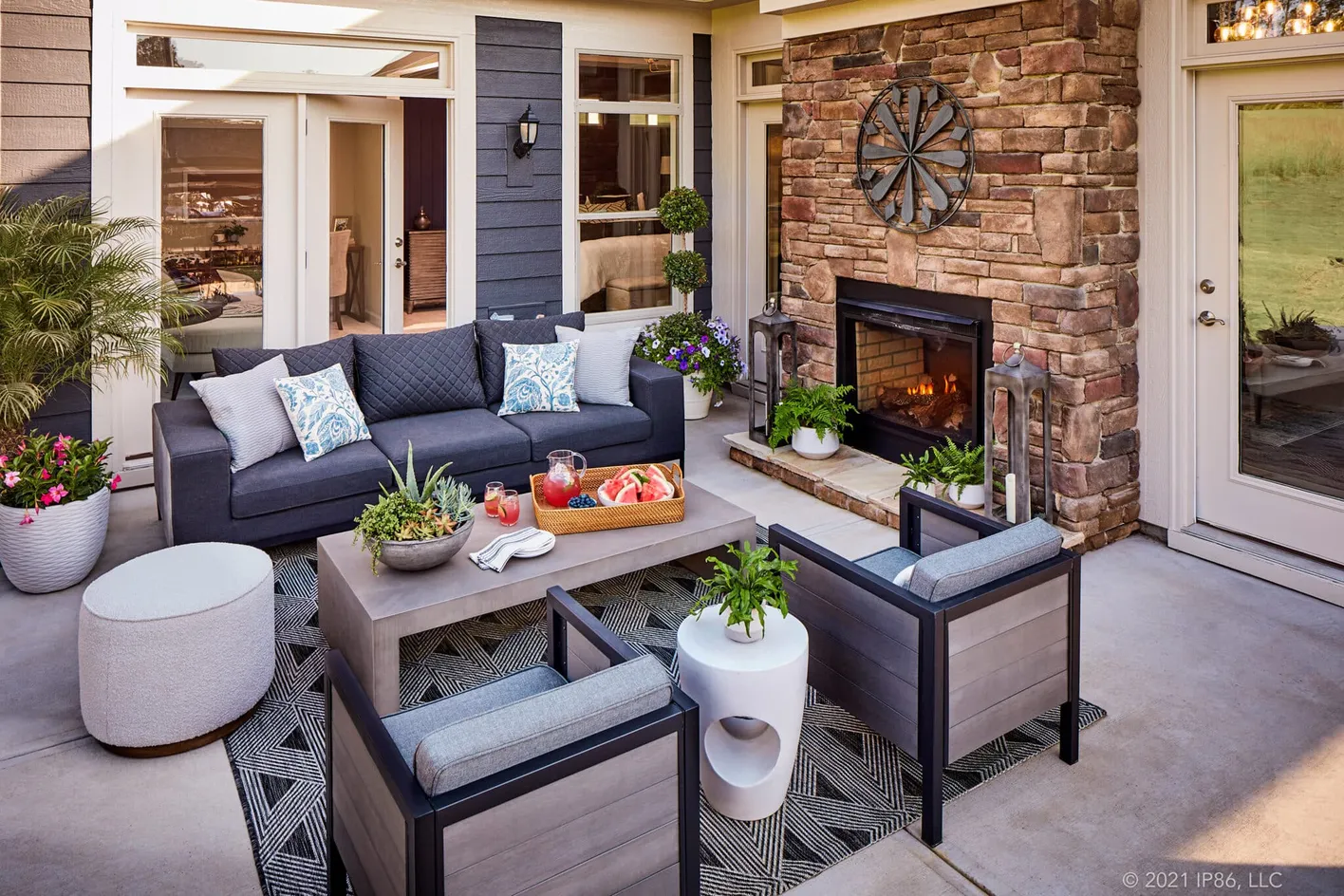 Covered patio with cozy seating and a stone fireplace for year-round outdoor living