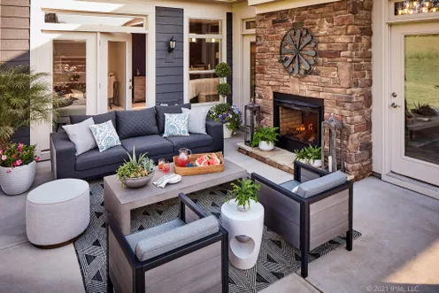 Covered patio with cozy seating and a stone fireplace for year-round outdoor living